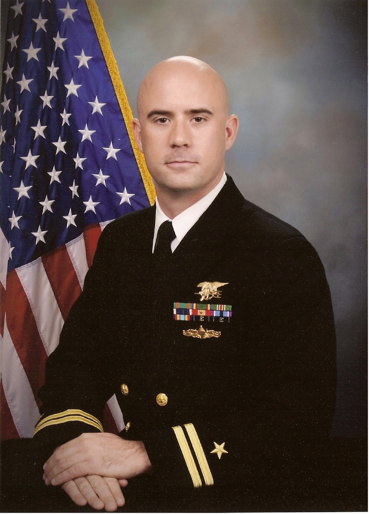 Official U.S. Navy portrait in dress blues in front of the American flag